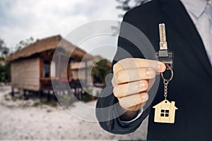 Rent a Bungalow on the beach for a holiday. man buying new house. hand receiving house key. Close up hand holding house key