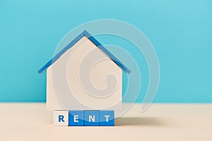 Rent house. Mortgage. Booking accommodation. Copy space. House miniature on wooden blocks with text on blue and white