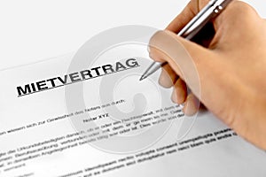 Rental agreement form with signing hand with the German Word Mietvertrag