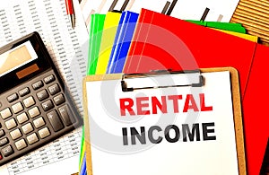 RENTAL INCOME text written on paper clipboard with chart and calculator