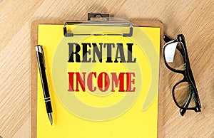 RENTAL INCOME text on a yellow paper on wooden background