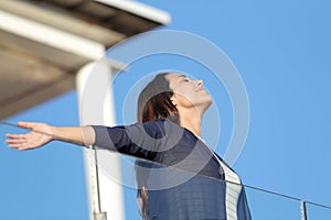Renter woman breathing fresh air in an apartment balcony photo