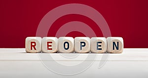 Reopen concept after the coronavirus pandemic. The word reopen on wooden blocks with red background