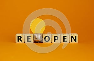 Reopen symbol. Wooden cubes with word \'reopen\'. Yellow light bulb.