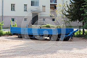 Repainted blue with rusted patches elongated old heavily used truck trailer parked on gravel parking lot