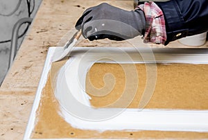 Repainting kitchen cabinet doors with white chalk paint indoors at home.