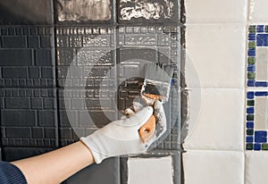 Repainting old dated kitchen ceramic tile back wall with modern gray chalk paint indoors at home. photo
