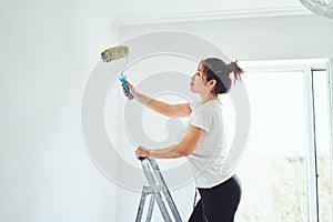 Repair in the apartment, the girl makes repairs in the apartment, paint the walls with a roller