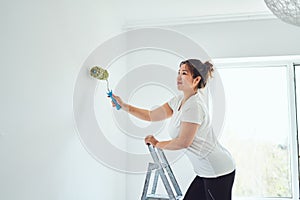 Repair in the apartment, the girl makes repairs in the apartment, paint the walls with a roller