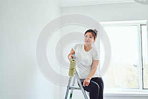 Repair in the apartment, the girl makes repairs in the apartment, paint the walls with a roller