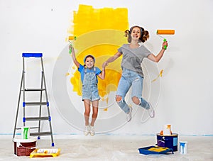 Repair in apartment. Happy family mother and child daughter jumping and paints wall