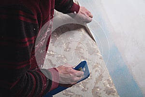 Repair the apartment. Worker glues the wallpaper to the wall