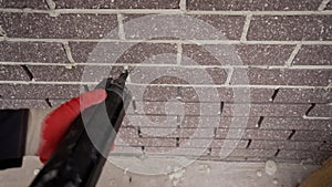 Repair in apartments and houses concept. The master sews seams on the brickwork. Joints in brickwork. Grouting with