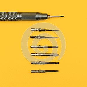 Repair background, screwdriver tool set with replaceable metal bits on a yellow background