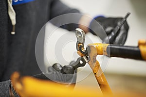 Repair of a bicycle: person disassembling an orange bike at his repair shop