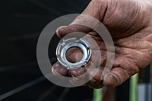 Repair bicycle wheel. Spoke key in the mechanic's hand. Rear wheel of a mountain bike on a black background. Dirty hands and