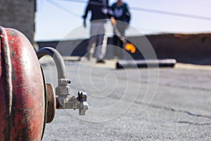 Repair of bitumen roof with roll surfacing material with fire gas burner close-up, front and background blurred with bokeh effect
