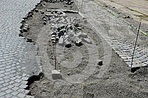 Repair of cobblestone road. between the joints of the cube is poured asphalt which is sprinkled from the top with fine white silic