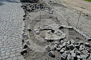 Repair of cobblestone road. between the joints of the cube is poured asphalt which is sprinkled from the top with fine white silic