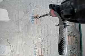 Repair concept, repair tools, builder worker with electric hammer drill making hole in wall in apartment. electric drill. perforat