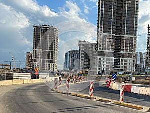 Repair and construction of a road with temporary road signs and cones against the background of beautiful tall new buildings