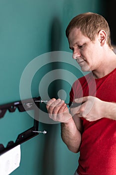 Repair and decoration. `husband for an hour` service. a man attaches a TV mount to a wall.