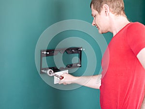 Repair and decoration. `husband for an hour` service. a man attaches a TV mount to a wall.