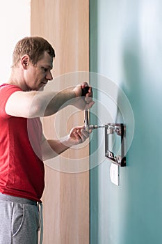 Repair and decoration. `husband for an hour` service. a man attaches a TV mount to a wall.