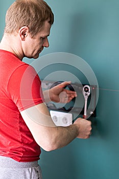 Repair and decoration. `husband for an hour` service. a man attaches a TV mount to a wall.