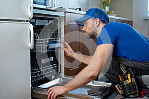 Repair of dishwashers. Repairman repairing dishwasher in kitchen