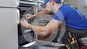 Repair of dishwashers. Repairman repairing dishwasher in kitchen