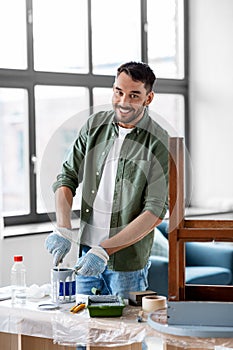 man stirring can with grey color paint at home