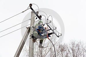 Repair of electrical networks. Power electrician lineman at work on pole. Electrician are climbing on electric poles to install