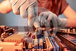 A repair engineer holds a RAM chip with his hands, inserts the RAM into the socket of the computer`s motherboard