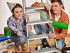 Repair family by happy couple building home using ladder.