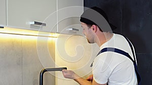 Repair of the faucet in the kitchen near the sink. A plumber in the kitchen installs a new water tap