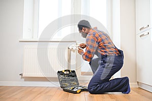 Repair heating radiator close-up. African man repairing radiator with wrench. Removing air from the radiator