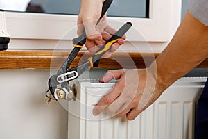 Repair heating radiator close-up. man repairing radiator with wrench.