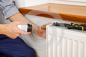 Repair heating radiator close-up. man repairing radiator with wrench.