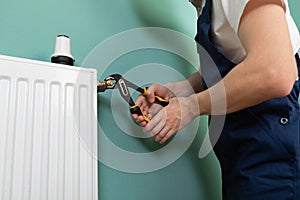 Repair heating radiator close-up. man repairing radiator with wrench.