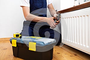 Repair heating radiator close-up. man repairing radiator with wrench.