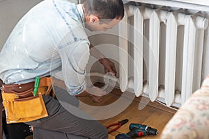 Repair heating radiator close-up. man repairing radiator with wrench. Removing air from the radiator.