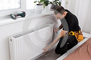Repair heating radiator close-up. man repairing radiator with wrench. Removing air from the radiator