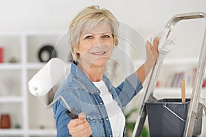Repair home elderly woman holding paint roller for wallpaper