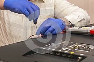 Repair of LCD TV, engineer in gloves with screwdriver removes the back panel of monitor. Selective focus, close-up