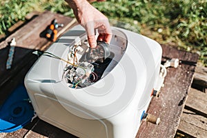 Repair and maintenance of the water heater. Man`s hands close-up holding detail for repair. Outdoor