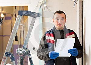 Repair man standing in apartment with documentation