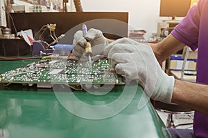 The repair man using digital multimeter measurement on circuit of PCB board.