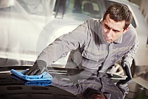 Repair man worker polishing automobile car body in garage