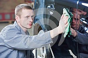 Repair man worker polishing automobile car body in garage